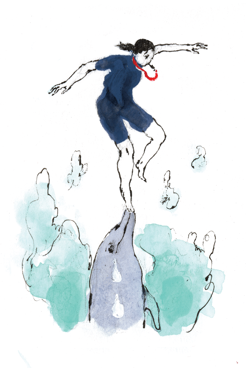 woman in a blue swimsuit with a red whistle balancing on the nose of a dolphin